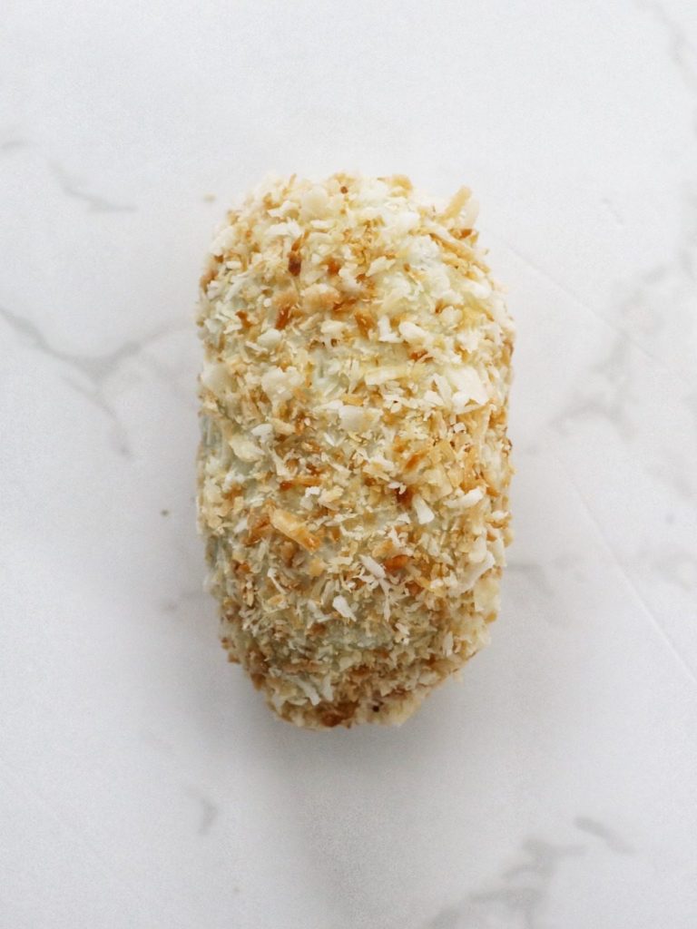 white chocolate covered date filled with mango pate de fruits and tumbled in roasted coconut