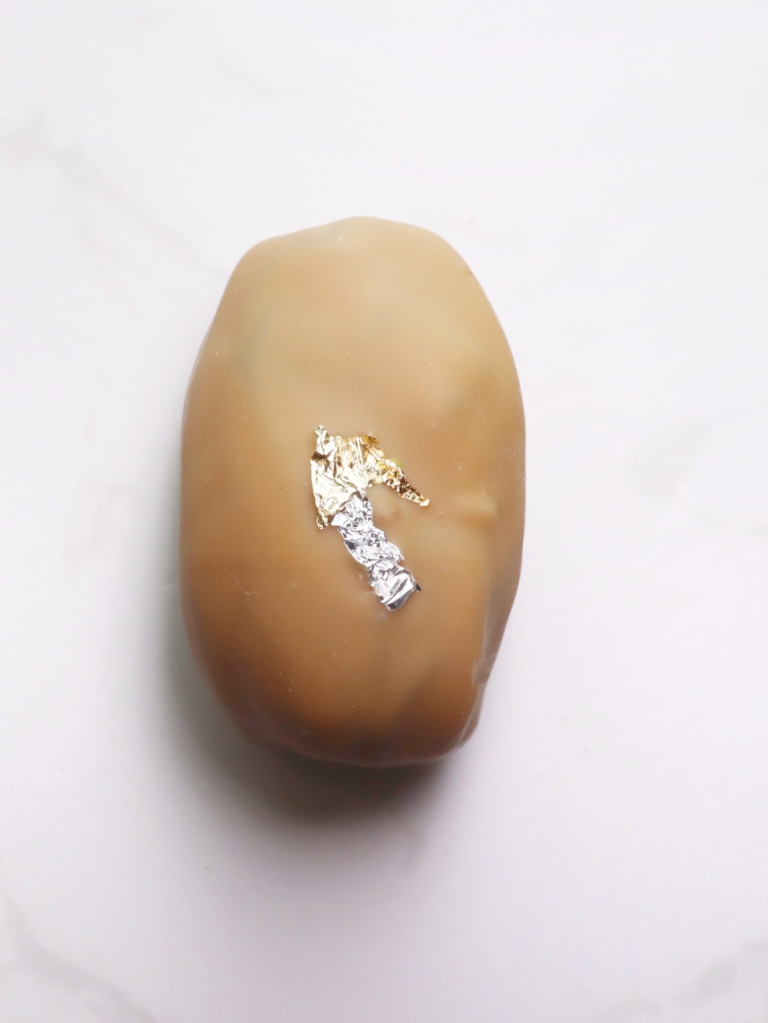 caramel chocolate coated date infused with a coffee praline and topped with silver and gold leaf
