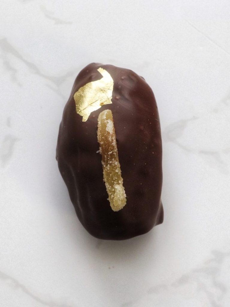 dark chocolate covered date filled with ginger and topped with gold leaf for flair!